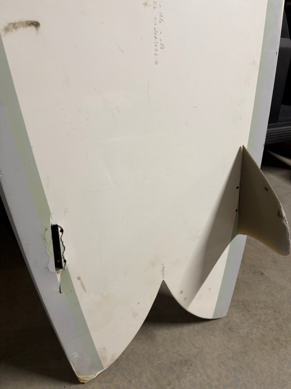 Epoxy twin fin with one fin box torn out of the tail